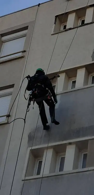 Cordiste de Marseille en travaux en hauteur de lavage haute pression de façade d'immeuble