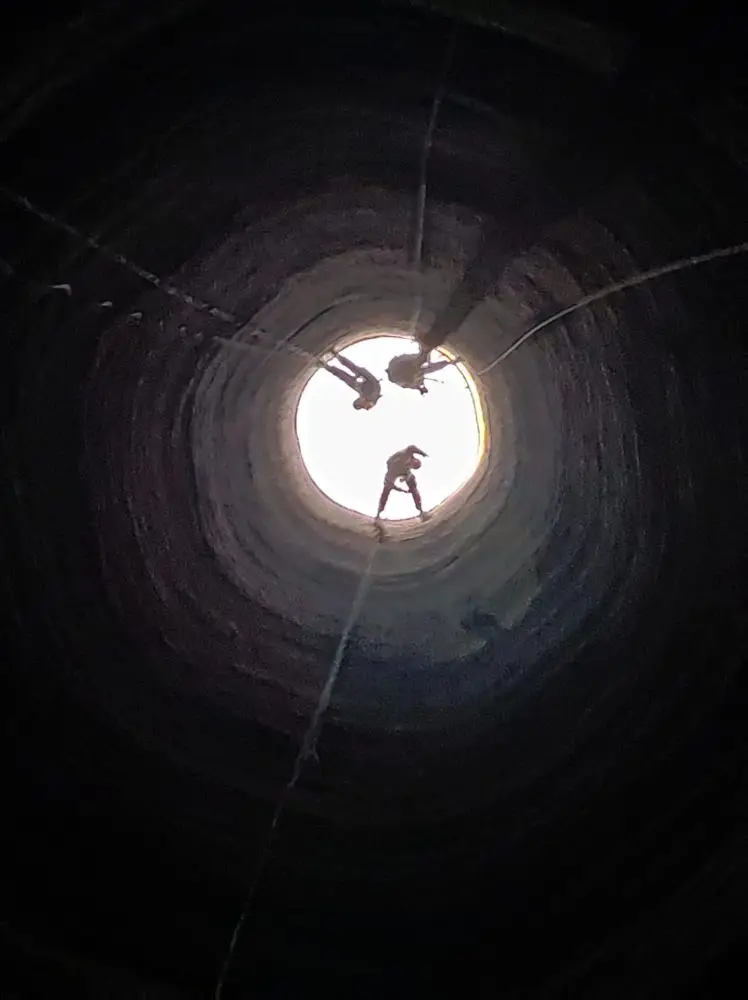 Vue de l'intérieur de la cheminée où l'on voit nos trois cordistes en action à une quinzaine de mètres de distance.