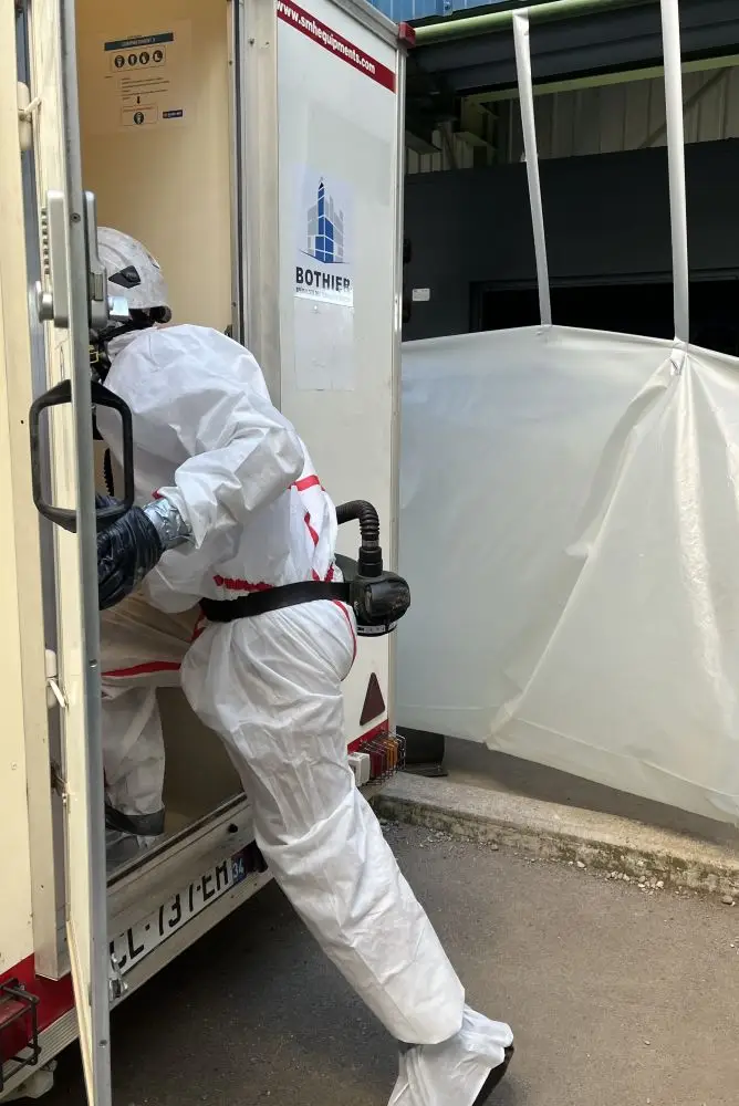 Technicien cordiste de BOTHIER entrant dans une Unité Mobile de Décontamination amiante